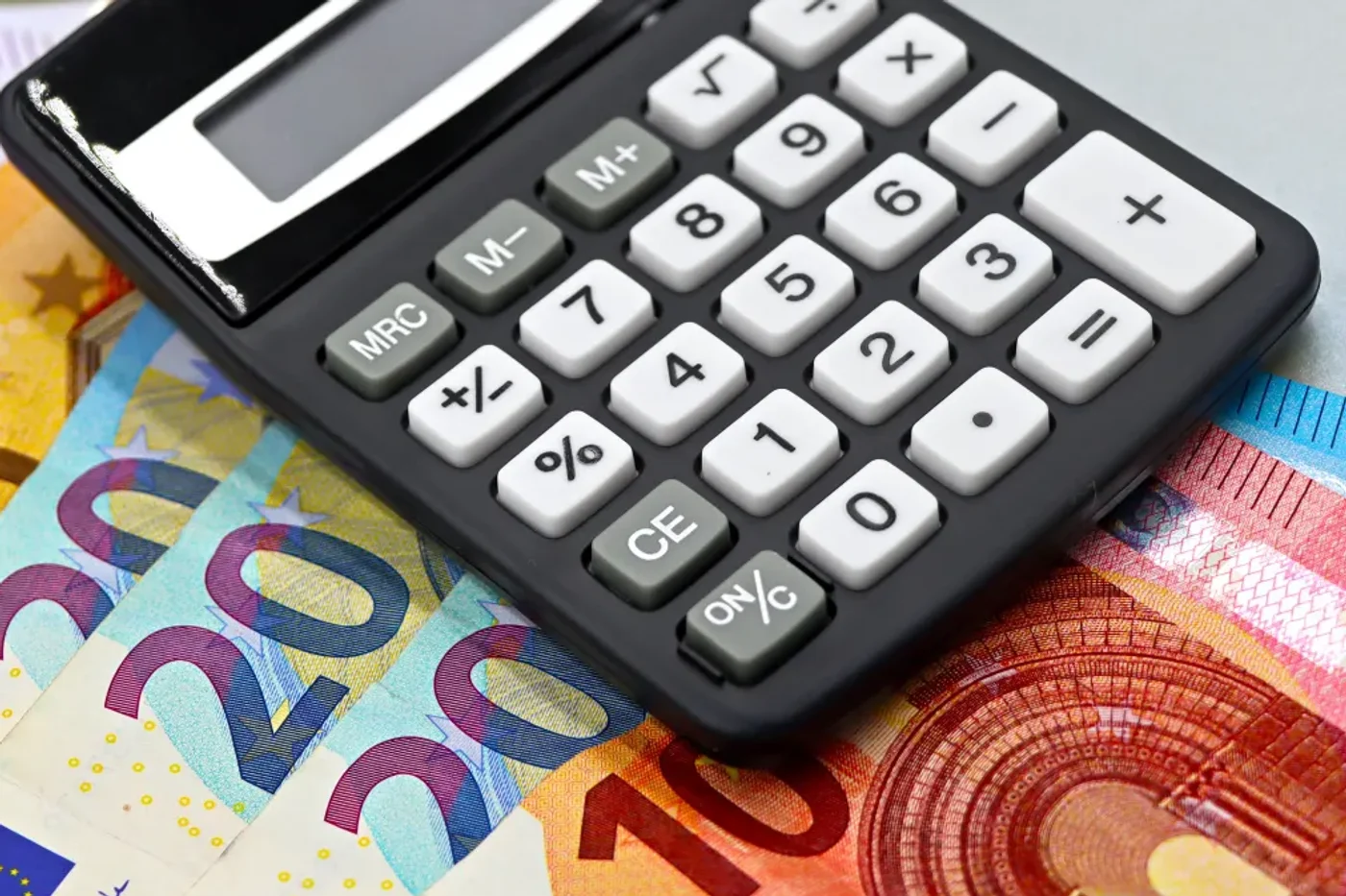 Calculatrice posée sur des billets en euros, illustration du calcul du coût complet d'un envoi vers les Comores